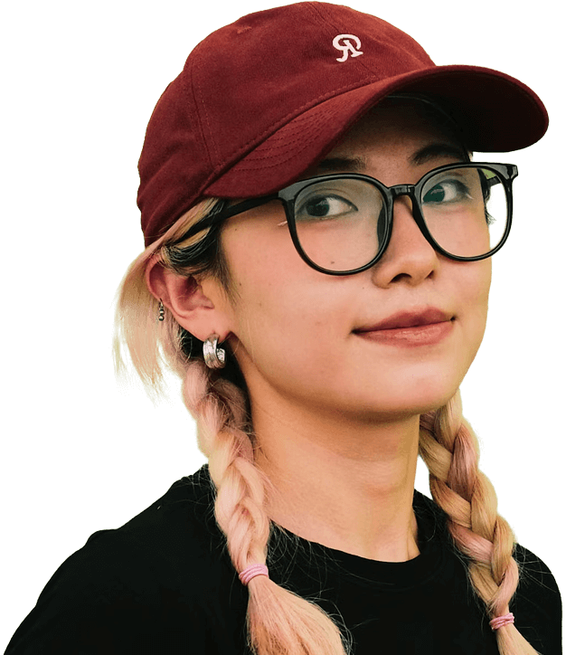 A young bespectacled woman wearing braided pigtails and a burgundy baseball cap looks confidently at the viewer